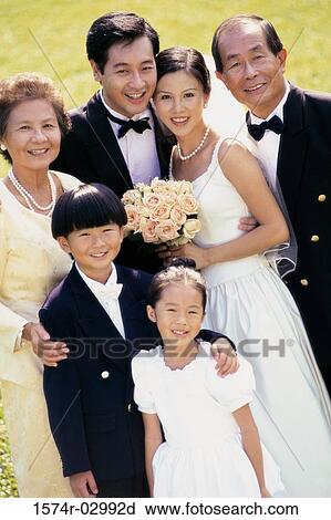 Stock Image - Portrait of a newlywed couple standing with their parents. Fotosearch