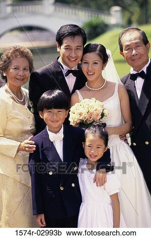 Stock Image - Portrait of a newlywed couple standing with their parents. Fotosearch