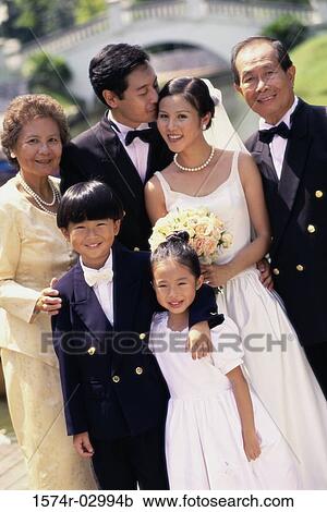 Stock Image - Portrait of a newlywed couple standing with their parents. Fotosearch