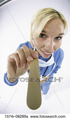 Portrait of a nurse holding a tongue depressor View Large Photo Image Stock Image - Portrait of a nurse holding a tongue depressor. Fotosearch
