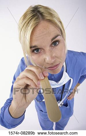 Stock Image - Portrait of a nurse holding a tongue depressor. Fotosearch