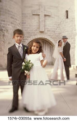 Stock Image - Portrait of a ring bearer and a flower girl standing in front of a church. Fotosearch