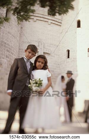 Stock Image - Portrait of a ring bearer and a flower girl standing in front of a church. Fotosearch