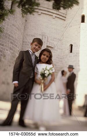 Stock Image - Portrait of a ring bearer and a flower girl standing in front of a church. Fotosearch
