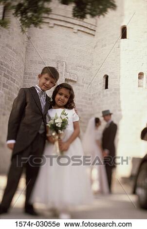 Stock Image - Portrait of a ring bearer and a flower girl standing in front of a church. Fotosearch