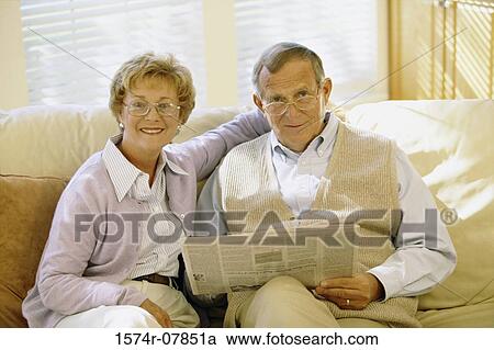 Portrait of a senior couple sitting on a couch reading a newspaper View Large Photo Image Stock Image - Portrait of a senior couple sitting on a couch reading a newspaper. Fotosearch
