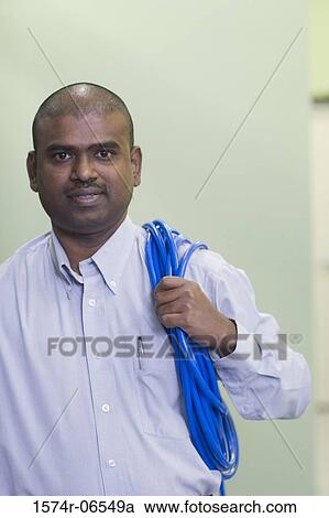 Stock Image - Portrait of a technician carrying computer cables on his shoulder. Fotosearch