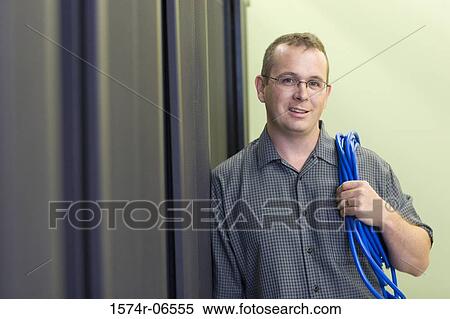 Stock Photography - Portrait of a technician carrying computer cables on his shoulder. Fotosearch