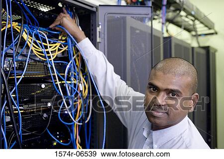 Stock Photo - Portrait of a technician connecting computer cables on a network server. Fotosearch