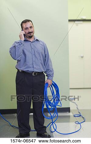Portrait of a technician holding computer cables talking on a mobile phone View Large Photo Image Stock Photo - Portrait of a technician holding computer cables talking on a mobile phone. Fotosearch