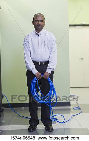 Stock Photo - Portrait of a technician holding computer cables. Fotosearch