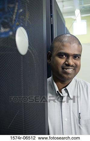Stock Image - Portrait of a technician smiling in a server room. Fotosearch