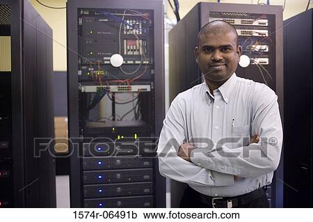Stock Image - Portrait of a technician standing in front of network servers. Fotosearch