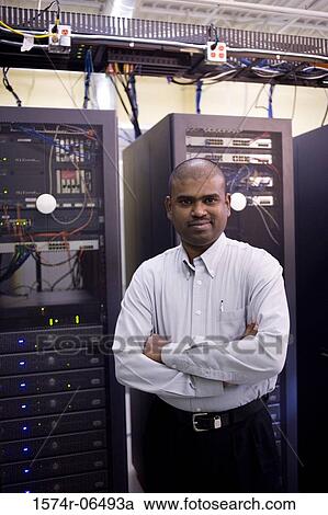 Stock Image - Portrait of a technician standing in front of network servers. Fotosearch