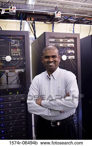 Stock Image - Portrait of a technician standing in front of network servers. Fotosearch