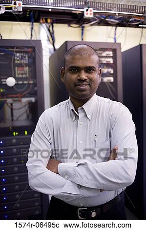 Stock Image - Portrait of a technician standing in front of network servers. Fotosearch