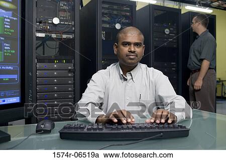 Portrait of a technician using a computer with another technician standing behind him View Large Photo Image Stock Image - Portrait of a technician using a computer with another technician standing behind him. Fotosearch