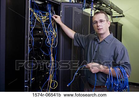 Stock Image - Portrait of a technician with computer cables in a server room. Fotosearch