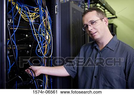 Stock Image - Portrait of a technician with computer cables in a server room. Fotosearch