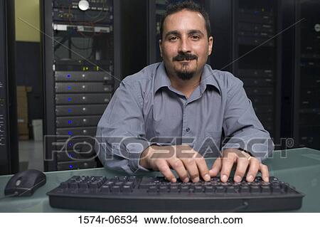 Portrait of a technician working on a computer in a server room View Large Photo Image Picture - Portrait of a technician working on a computer in a server room. Fotosearch