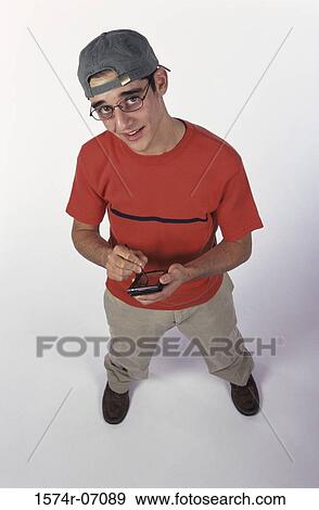 Stock Photo - Portrait of a teenage boy holding a hand held device. Fotosearch