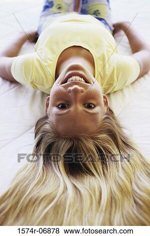 Stock Photo - Portrait of a teenage girl lying on a bed smiling. Fotosearch