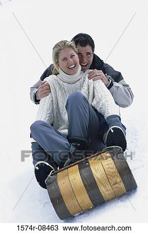 Stock Image - Portrait of a young couple sitting on a sled. Fotosearch