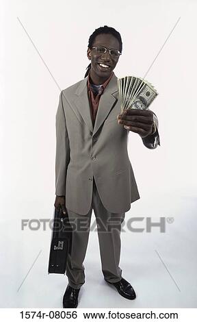 Stock Photograph - Portrait of a young man holding paper money and a briefcase. Fotosearch