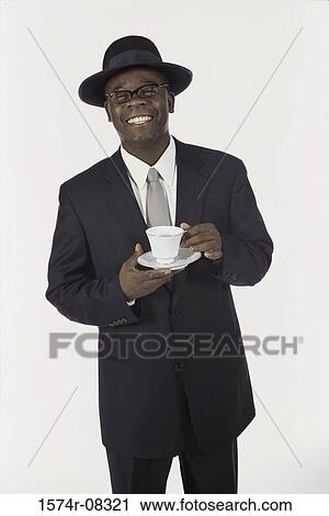 Portrait of a young man in a suit holding cup and saucer View Large Photo Image Stock Image - Portrait of a young man in a suit holding cup and saucer. Fotosearch