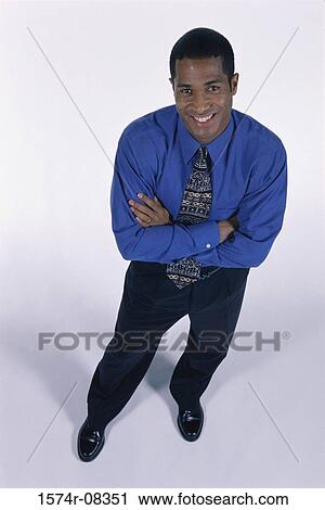 Stock Image - Portrait of a young man standing with his arms folded. Fotosearch