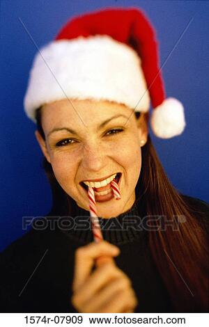 Stock Photo - Portrait of a young woman eating a candy cane. Fotosearch
