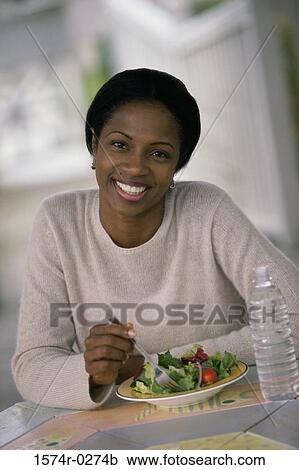 Stock Image - Portrait of a young woman eating fruit salad. Fotosearch
