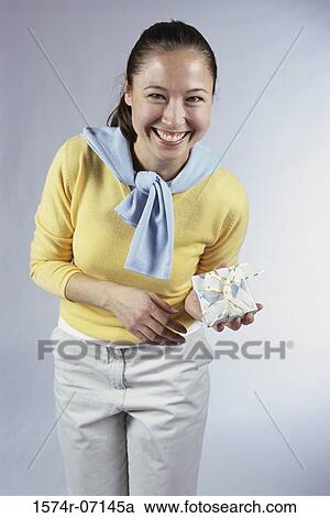 Portrait of a young woman holding a gift View Large Photo Image Stock Image - Portrait of a young woman holding a gift. Fotosearch