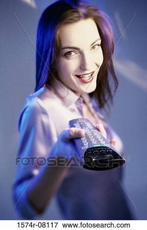 Portrait of a young woman holding a remote control View Large Photo Image Stock Photo - Portrait of a young woman holding a remote control. Fotosearch
