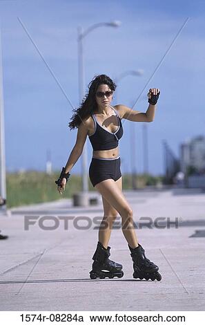 Stock Image - Portrait of a young woman inline skating on road. Fotosearch