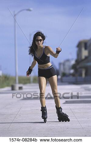 Stock Image - Portrait of a young woman inline skating on road. Fotosearch