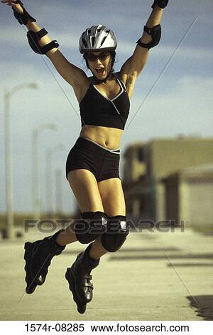 Stock Photography - Portrait of a young woman jumping while wearing inline skates. Fotosearch