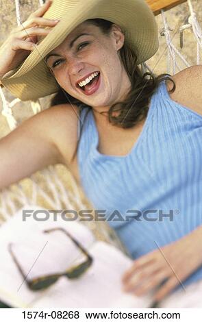 Portrait of a young woman lying in a hammock wearing a hat smiling View Large Photo Image Stock Photo - Portrait of a young woman lying in a hammock wearing a hat smiling. Fotosearch