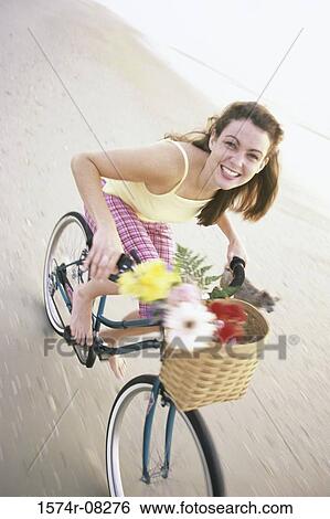 Portrait of a young woman riding a bicycle with her dog running alongside View Large Photo Image Stock Photograph - Portrait of a young woman riding a bicycle with her dog running alongside. Fotosearch