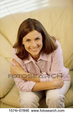 Stock Photograph - Portrait of a young woman sitting on a couch. Fotosearch