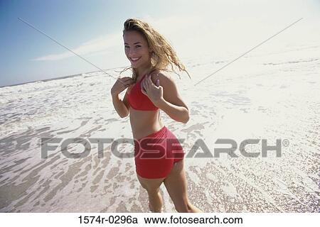 Stock Image - Portrait of a young woman smiling at the beach. Fotosearch