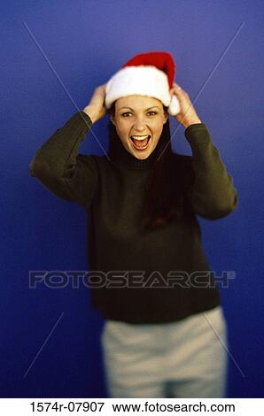 Portrait of a young woman wearing a Santa hat smiling View Large Photo Image Stock Photo - Portrait of a young woman wearing a Santa hat smiling. Fotosearch