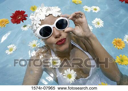 Stock Photography - Portrait of a young woman wearing sunglasses in a swimming pool. Fotosearch