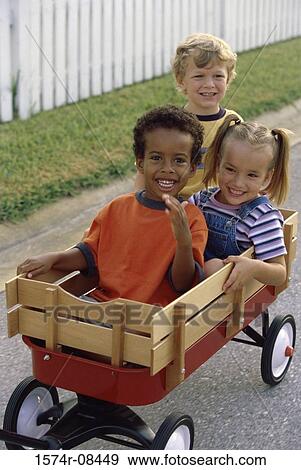 Portrait of two boys and a girl playing with a push cart View Large Photo Image Stock Photo - Portrait of two boys and a girl playing with a push cart. Fotosearch