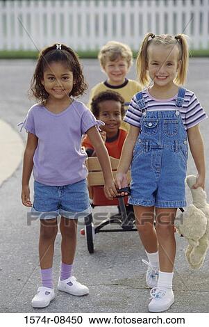 Stock Image - Portrait of two boys and two girls playing with a push cart. Fotosearch