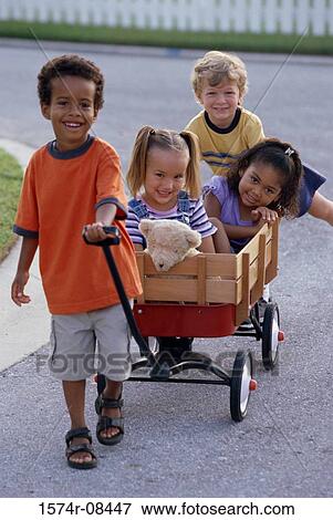 Stock Photo - Portrait of two boys and two girls playing with a push cart. Fotosearch