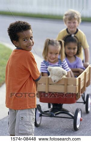 Stock Photo - Portrait of two boys and two girls playing with a push cart. Fotosearch