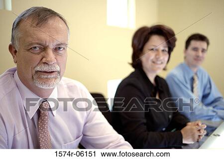 Portrait of two businessmen and a businesswoman smiling in an office View Large Photo Image Stock Image - Portrait of two businessmen and a businesswoman smiling in an office. Fotosearch