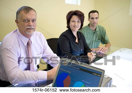 Stock Image - Portrait of two businessmen and a businesswoman sitting in an office. Fotosearch