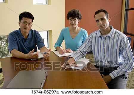 Portrait of two businessmen and a businesswoman sitting in an office View Large Photo Image Stock Image - Portrait of two businessmen and a businesswoman sitting in an office. Fotosearch